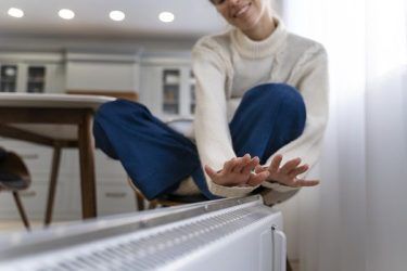 manos de mujer sobre radiador ahorro energía